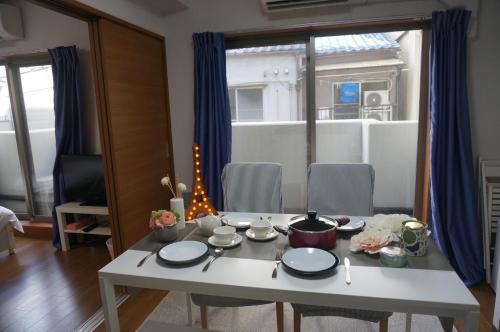 Ocean OTR Park View Bentencho في أوساكا: طاولة عليها أطباق في غرفة المعيشة