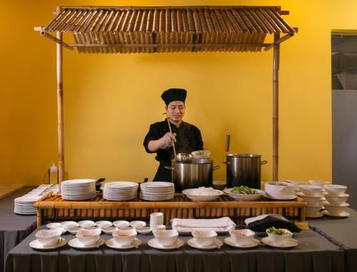 a chef standing in a kitchen preparing food at Pistachio Hotel Sapa in Sa Pa