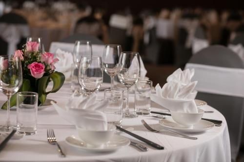 a white table with glasses and plates and flowers on it at Pistachio Hotel Sapa in Sa Pa