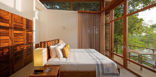 a bedroom with a bed and a large window at Tri by Amaya in Ahangama