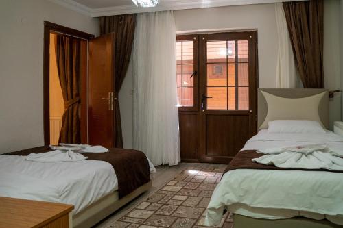 a hotel room with two beds and a window at Uzungöl Kuzey Park Pansiyon in Uzungöl