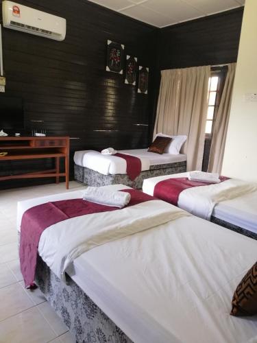 a room with three beds and a television in it at AsiaCamp Taman Negara Resort in Kuala Tahan