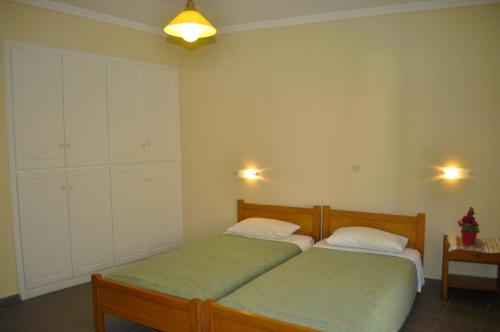a bedroom with two beds and a cabinet and lights at Holiday Studio Apartments yannis on Agios Gordios beach in Corfu in Agios Gordios