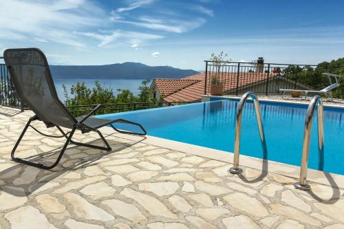 a chair sitting next to a swimming pool at Jovich Apartments 2 in Mošćenička Draga