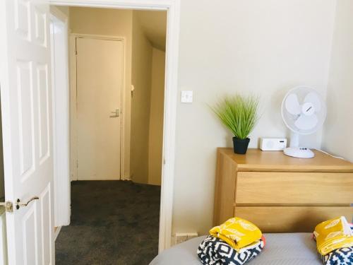 a bedroom with a bed and a dresser with a fan at Bright Apartment in the Heart of St Leonards in Hastings