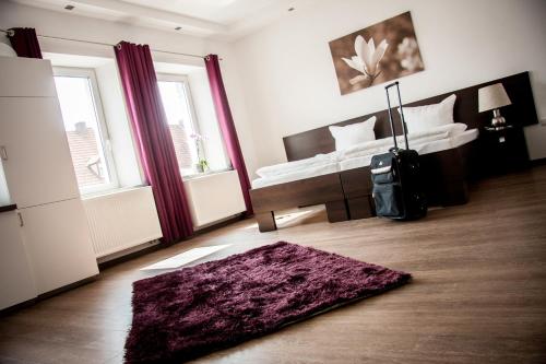 a bedroom with a bed and a purple rug at Aparthotel - Stadtvilla Premium in Schweinfurt