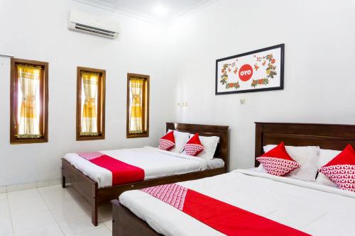 OYO 801 Hansa Homestay في باكيتان: سريرين في غرفة مع وسائد حمراء وبيضاء