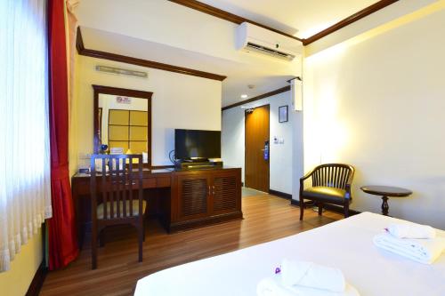 een hotelkamer met een bureau en een televisie bij Grand Business Inn in Bangkok