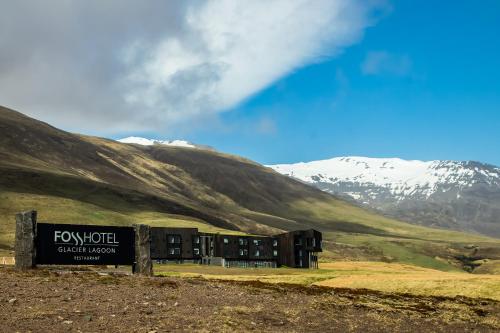 a building in a field with mountains in the background at Fosshotel Glacier Lagoon in Hnappavellir