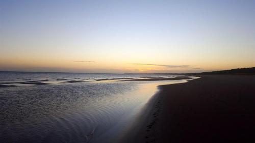 a beach at sunset with footprints in the sand at Fewo Wellenreiter Usedom 200 m zum Strand mit Balkon Parkplatz Wlan in Ostseebad Karlshagen