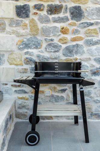 a black bench sitting in front of a stone wall at Marilena Natural Stone House, By Hellocrete in Pigi