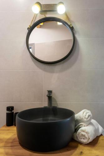 a bathroom with a black sink and a mirror at Marilena Natural Stone House, By Hellocrete in Pigi