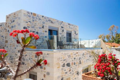 a stone building with a balcony and red flowers at Marilena Natural Stone House, By Hellocrete in Pigi