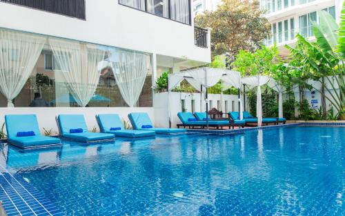 a pool with blue chairs and umbrellas next to a building at Home Chic Hotel in Phnom Penh
