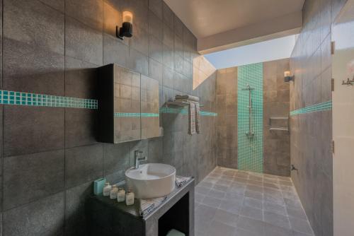 La salle de bains est pourvue d'un lavabo et d'une douche. dans l'établissement Boutique Beach All Inclusive Diving Hotel, à Dhigurah