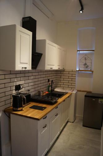 羅茲的住宿－Apartament Czekoladowy，厨房配有白色橱柜和木制台面