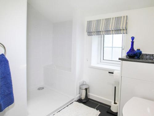 biała łazienka z toaletą i oknem w obiekcie Amolca w mieście Amlwch