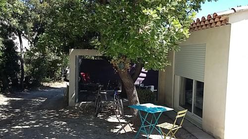 una mesa y sillas bajo un árbol al lado de un edificio en ChambreStudio bord de mer, Piscine et SPA en Six-Fours-les-Plages