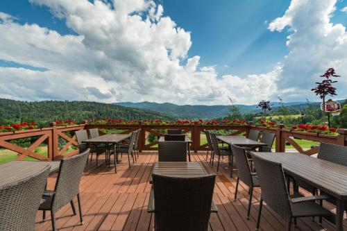 a patio with tables and chairs on a deck at Pod Brzozka in Cisna