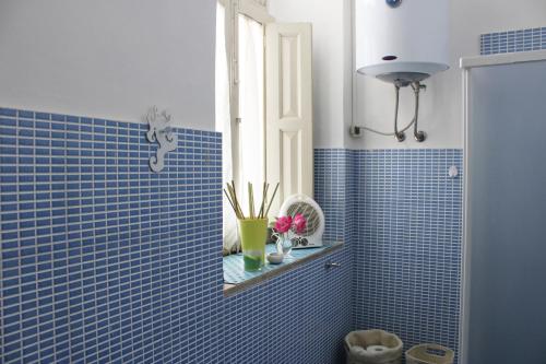 a bathroom with blue tiled walls and a window at Gemma di Luna in Catania