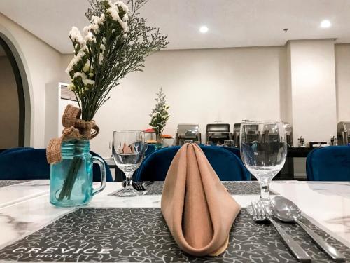 a table with a vase of flowers and glasses on it at CREVICE HOTEL in Davao City