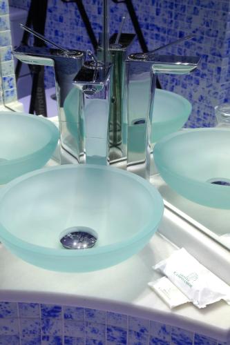 a bathroom sink with four glasses on a counter at Hotel Campoamor in Oviedo