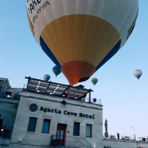 a hot air balloon flying over a building at Agarta Cave Hotel in Goreme