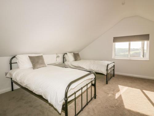 two beds in a white room with a window at The Beach Halt in Perranporth
