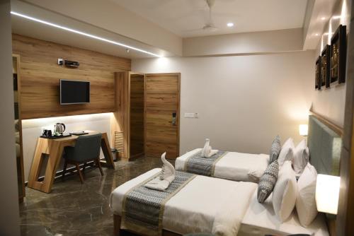 a hotel room with two beds and a desk at HOTEL HIRISA Unit Of Hotel Fortune Palace in Jamnagar