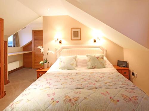 a bedroom with a large bed in a attic at Barras Cottage in Dwyran