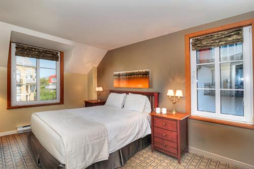 a bedroom with a bed and two windows at Place Saint Bernard Mont Tremblant in Mont-Tremblant