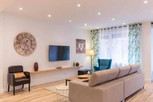 ein Wohnzimmer mit einem Sofa und einer Uhr an der Wand in der Unterkunft Bilbao Abando II by Aston Rentals in Bilbao