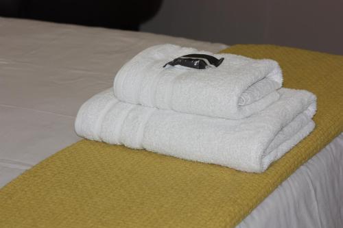 een stapel handdoeken bovenop een bed bij Bush Pillow Guest House in Otjiwarongo