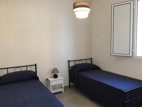 two beds with blue sheets in a room with a window at Casa Vigna da Michela in Favignana