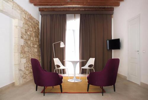 a room with chairs and a table and a window at Isabella di Castiglia Apartments in Siracusa