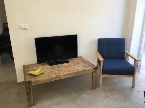 a wooden table with a tv and a blue chair at Casa Vigna da Michela in Favignana