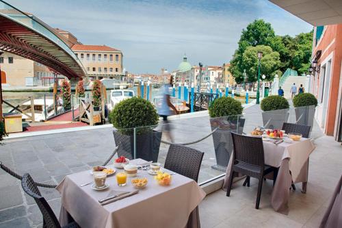 a restaurant with tables and chairs with a view of a river at Hotel Santa Chiara in Venice