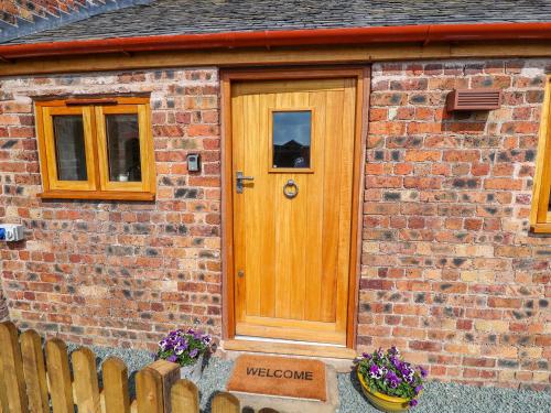 a wooden door on a brick house with flowers at The Tractor Shed in Oswestry