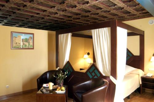 a hotel room with a bed and two chairs at Hotel Spa La Casa Mudéjar in Segovia