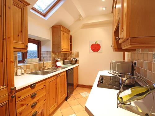 een keuken met houten kasten en een wastafel bij Barras Cottage in Dwyran