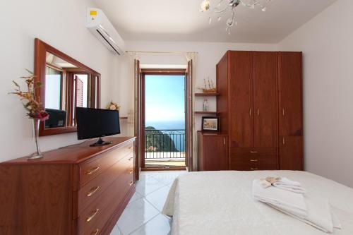 1 dormitorio con cama, TV y balcón en Lo Smeraldo Luxury Home Ravello by ElodeaGroup, en Scala