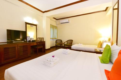 a hotel room with two beds and a television at Grand Business Inn in Bangkok