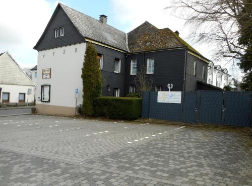 a black and white house with a fence at Hotel Böving in Breckerfeld