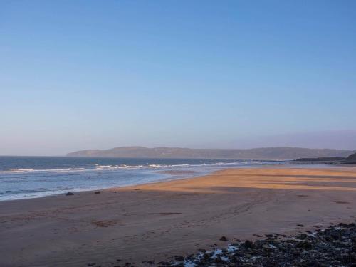 a beach with the ocean and mountains in the background at Beach Lookout in Benllech