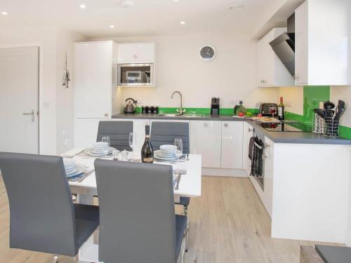 a kitchen with white cabinets and a table and chairs at Beach Lookout in Benllech