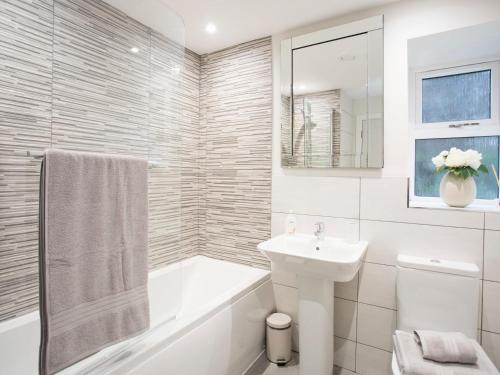 a white bathroom with a sink and a tub and a sink at The Beach Pad in Benllech