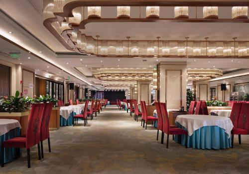 een restaurant met tafels en stoelen en een kroonluchter bij Jinmanfu International Hotel in Huadu