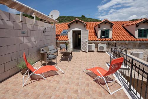 a patio with two chairs and a table and a house at Emily Apartment in Suđurađ