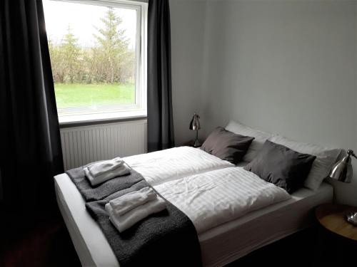 a bedroom with a bed with pillows and a window at Guesthouse Geldingaholt in Árnes