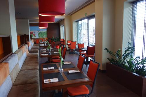 a dining room with wooden tables and red chairs at Desilva Inn Katowice Airport in Pyrzowice